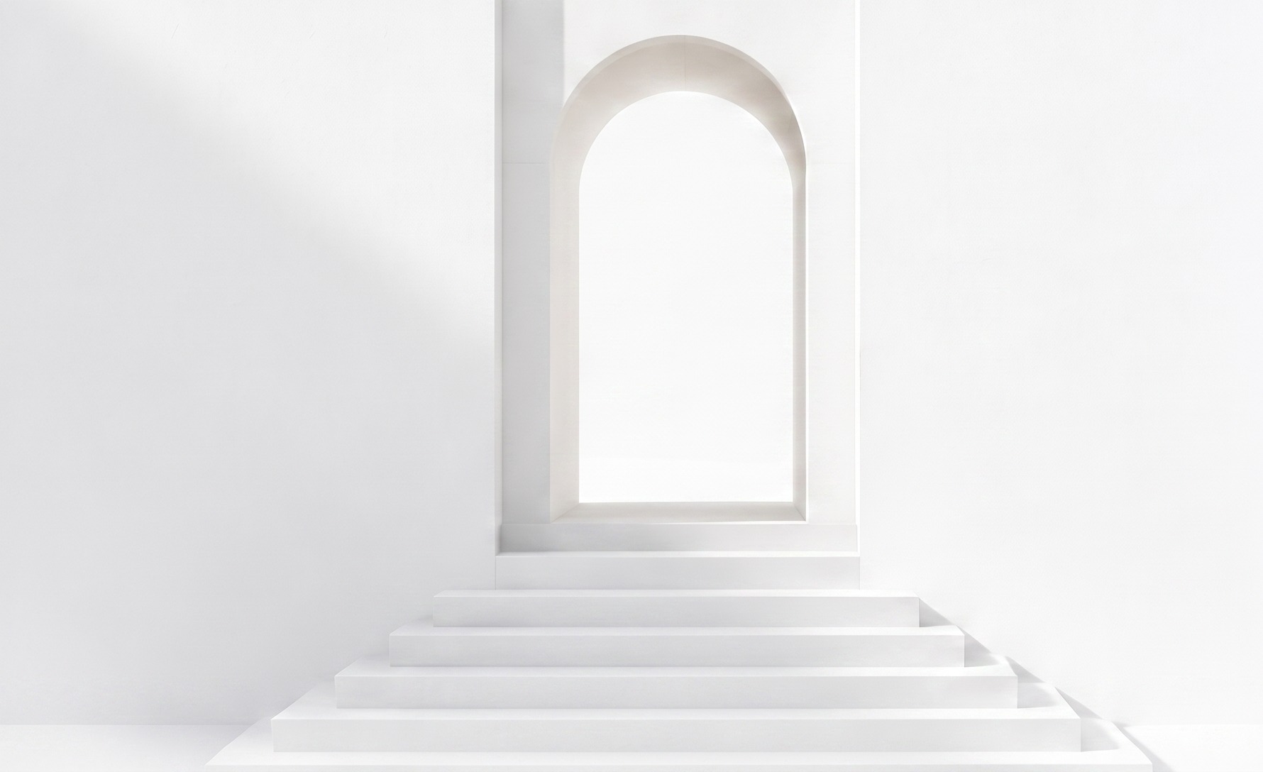 A minimalist white archway with a staircase leading up to it